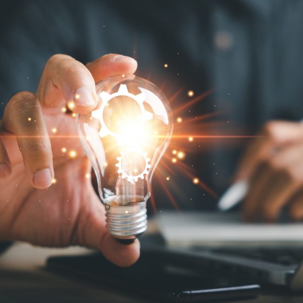 Smart business ideas, Businessman protects a glowing light bulb, symbolizing innovation and creativity. Illustrates the concept of brainstorming, solution, and successful profit in global business.